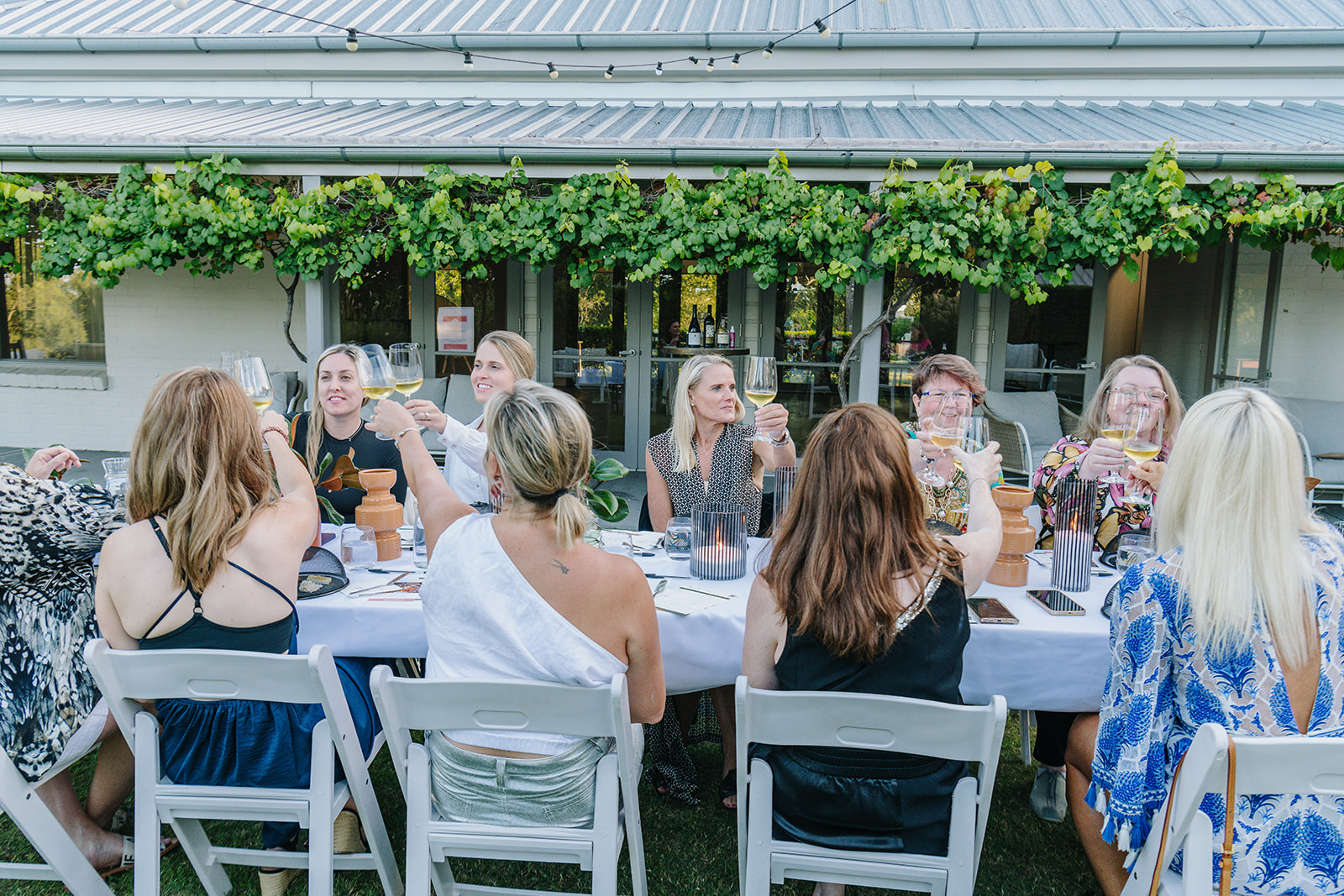 FemPowered Women toasting around a long table at an outdoor member dinner