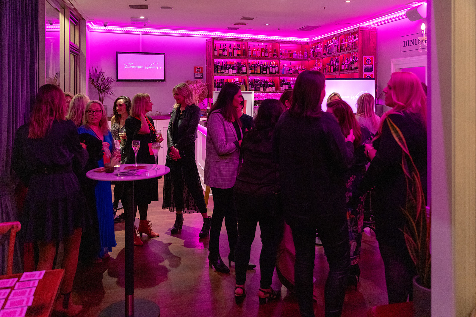 Women together under pink light at a FemPowered event